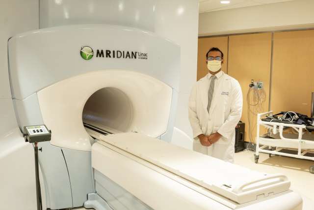 Dr. Amar U. Kishan stands with the MRIdian Linac, which is able to guide radiation treatment.