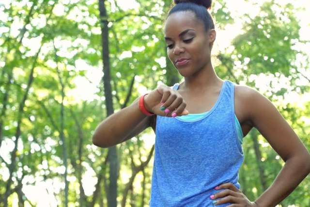 Woman in blue tank top checking smartwatch outdoors