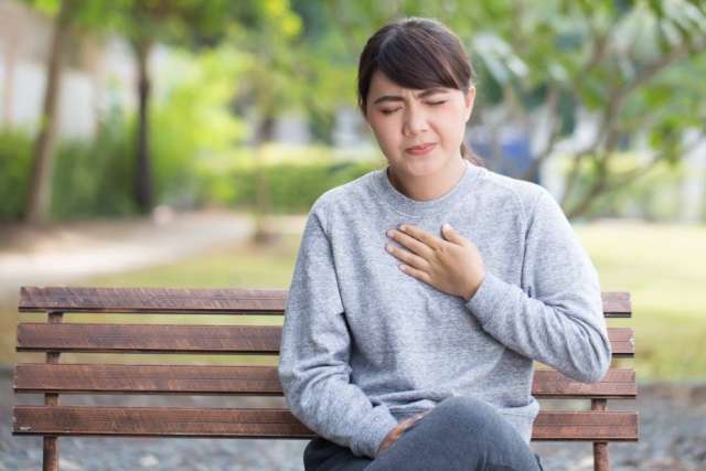 Woman on park bench clutching her chest