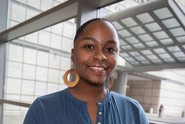Porchia Toussaint smiling headshot, blue top and circular earrings in glass atrium.