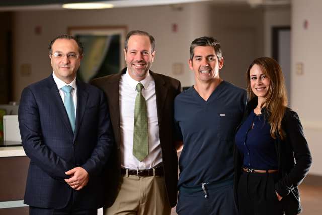 Four colleagues standing together in a modern office hallway