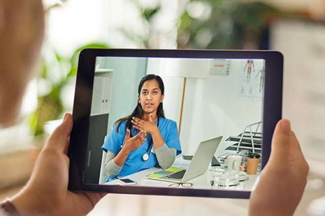 elderly woman holding an ipad on a video call with a medical professional for a telemedicine appointment