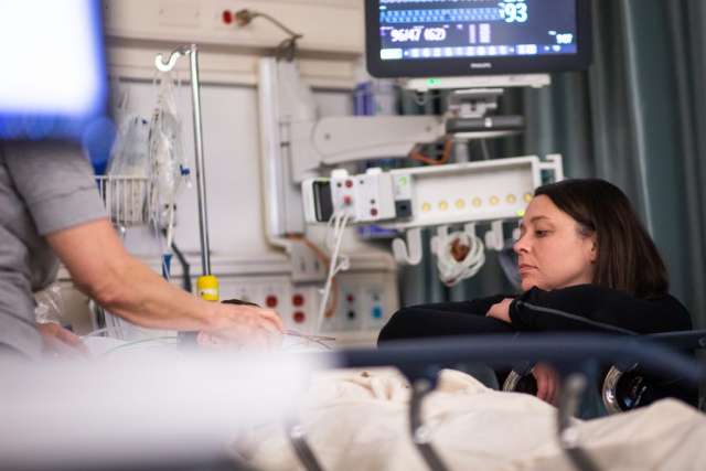 Karleen Wray sitting beside a child patient's bed post surgery