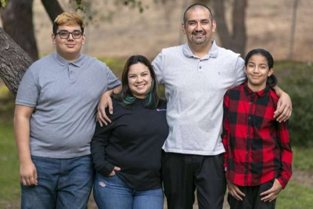 A smiling Lazaro Barajas with his family. From left to right: a teenage boy, a woman, a man, and a teenage girl.