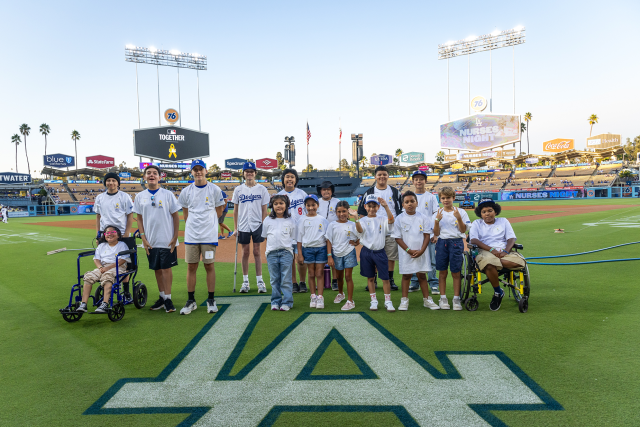 Pediatric cancer patients from UCLA Health pose on Dodger Stadium field during Childhood Cancer Awareness Month event.