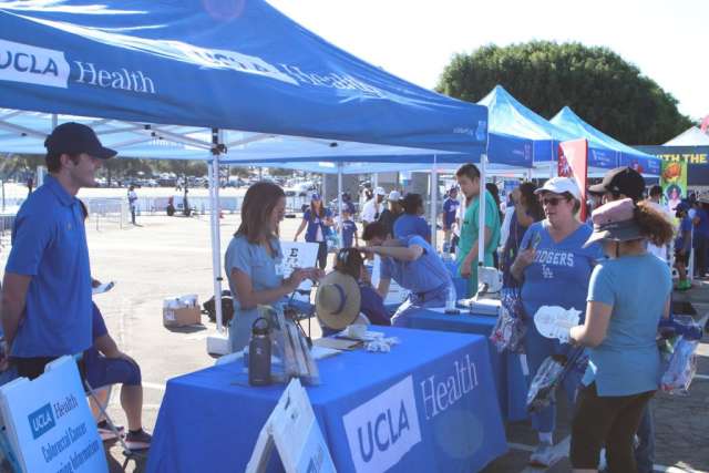 Fam Care Village booth at a health fair with staff and visitors under blue tents