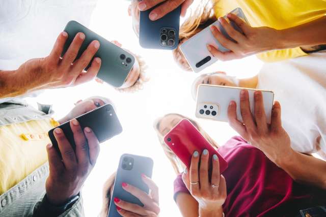 Hands holding smartphones in a circle seen from below