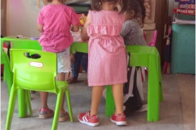 A 5-year-old girl with two prosthetic legs stands at a play table. She lost her mother, father and siblings in the earthquake in Turkey.