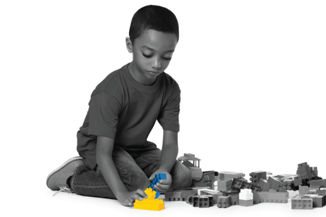 Black‑and‑white photo of a boy playing with colored toy blocks, alongside an image of surgeons operating in a brightly lit OR