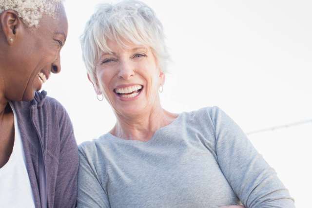 Two women smiling together outdoors, with their faces obscured.