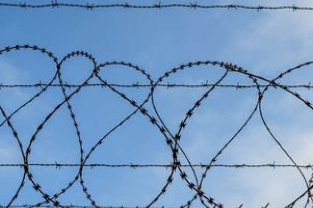 Barbed wire fencing against a blue sky.