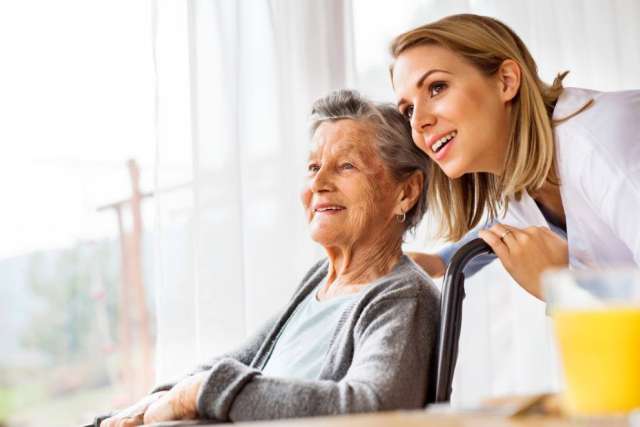 Caregiver smiling with elderly woman in wheelchair