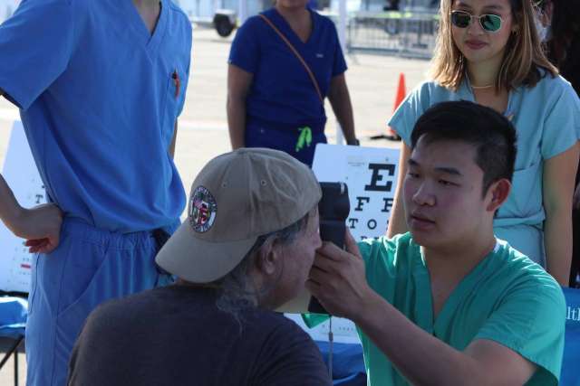 Volunteer uses forehead thermometer on a person.
