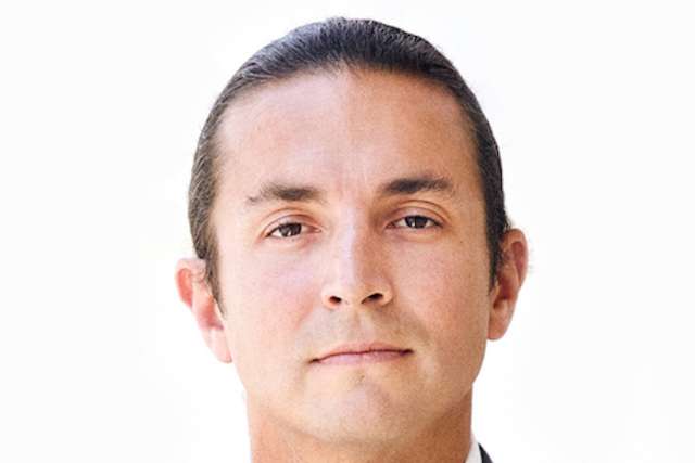 Headshot of Benjamin Ellingson with a blurred face, wearing a suit.