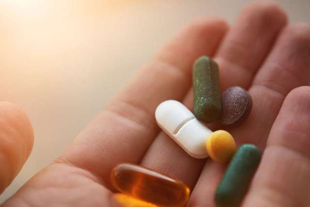 Hand holding assorted pills and capsules