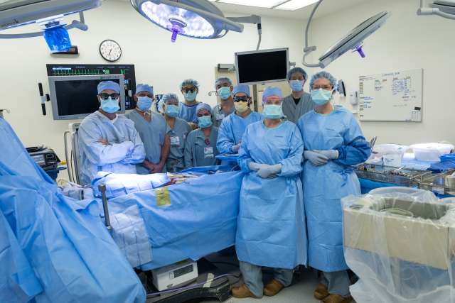 Surgical team in blue scrubs and masks in an operating room