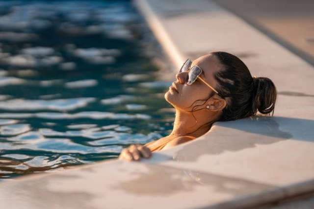 Woman relaxing at pool edge wearing sunglasses