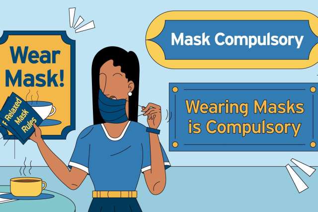 A person wearing a mask holds a book with mask mandates in a café setting.