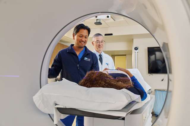 Medical scanner tunnel with two technicians loading a patient on the table