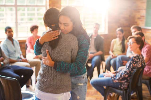 Two women hug at a cancer support group