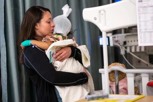 Karleen Wray holding a young girl, who has a bandage wrap around her head, after surgery