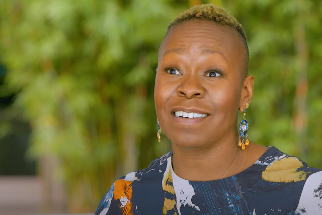 Melissa Watkins, sitting down in an outdoor setting, speaking to a camera for Philanthropy 