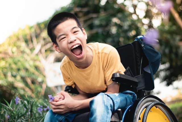 A child in a wheelchair with joyful smile.