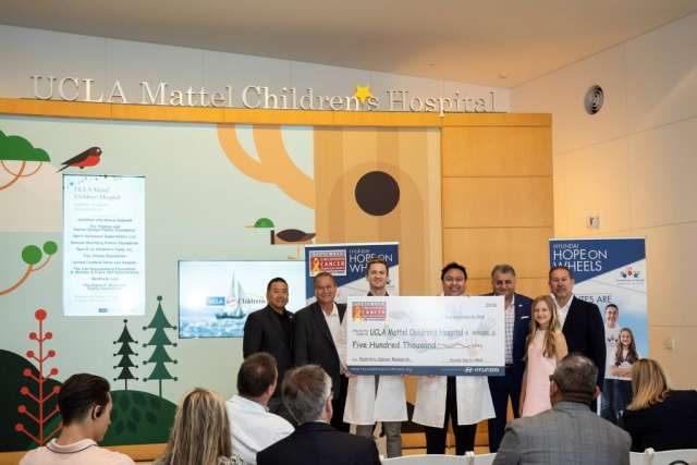  A group of 10 people, some in lab coats, hold a large check for $250,000, presented on a stage with a nature-themed backdrop.