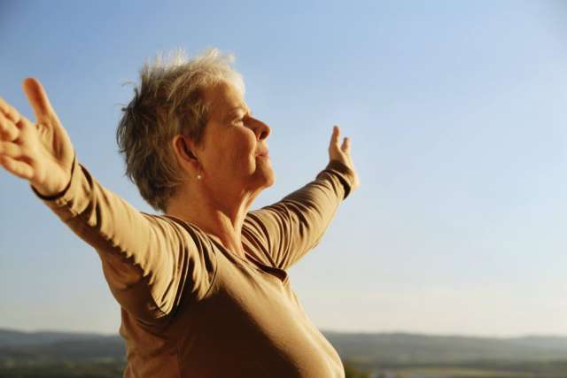Woman outdoors with arms outstretched facing sky