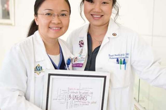Two healthcare professionals in white coats holding a framed print with the words '3 Wishes' and related text.