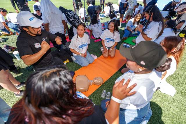 Children gathered on grass to learn CPR.