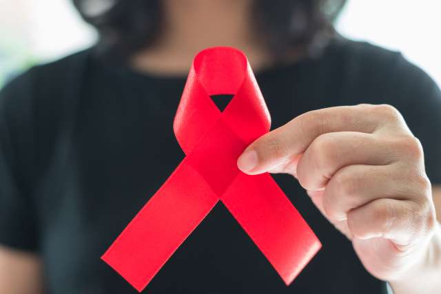 Woman holding red ribbon for World AIDS Day