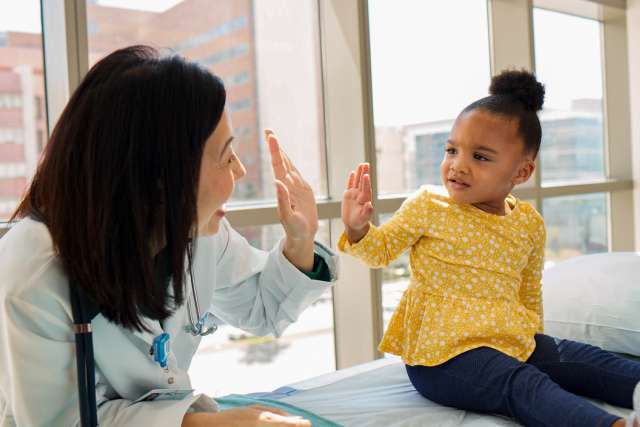 A doctor high-fiving a child in a UCLA Health medical location.