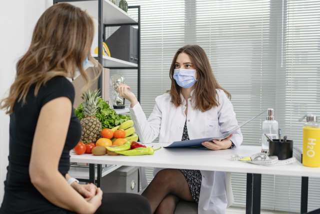 masked doctor consults patient