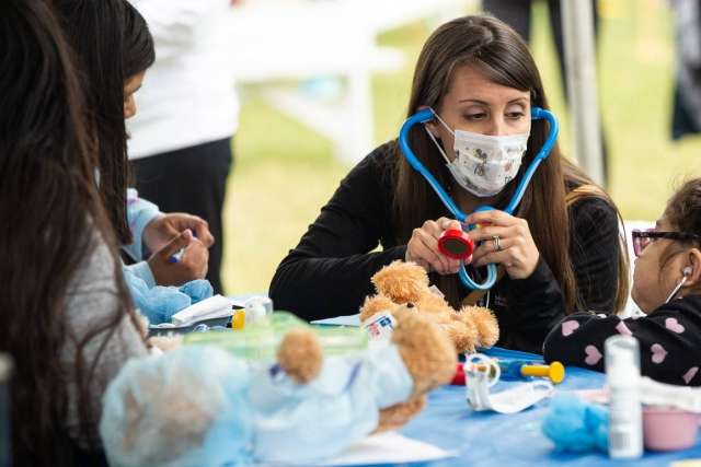 Children participate in a teddy bear clinic, using toy stethoscopes and stuffed bears.