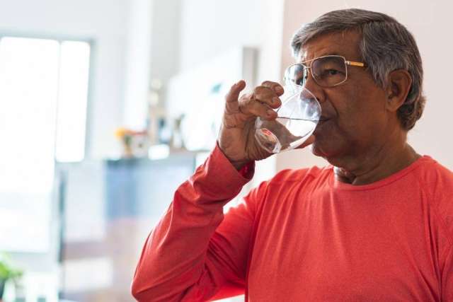 Man in red shirt drinking a glass of water