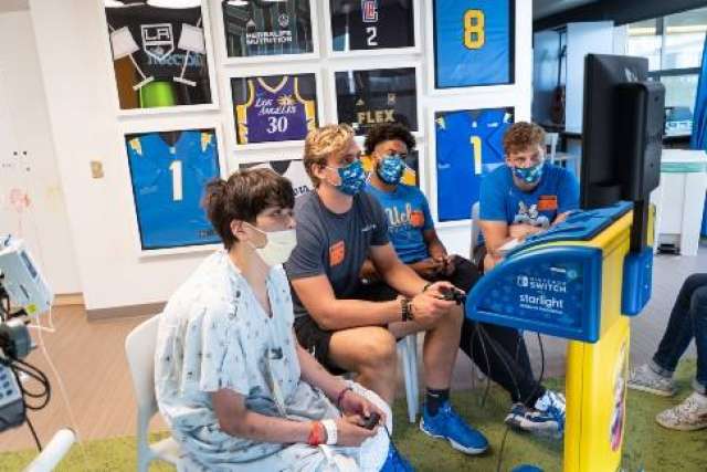 Four masked players seated at console focused on screen