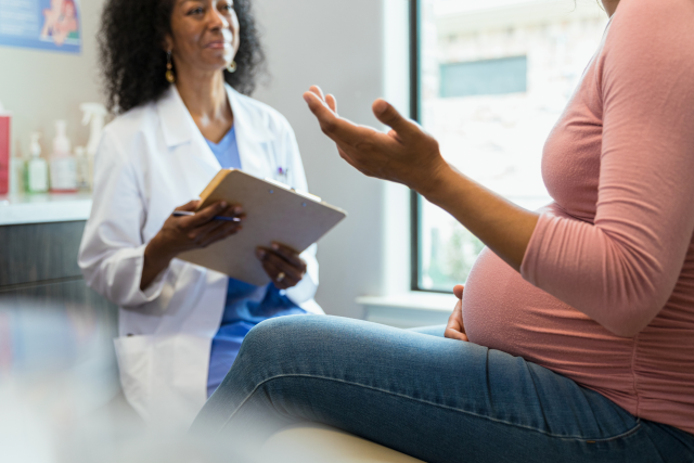 A pregnant woman speaks with her doctor.