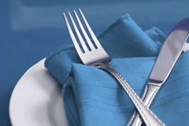 Silverware resting on a blue napkin placed on a white plate.