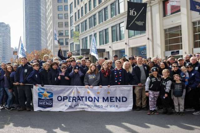 UCLA Operation Mend team and veterans marching in the 2019 Veterans Day Parade holding a banner that reads “Healing the Wounds of War.”