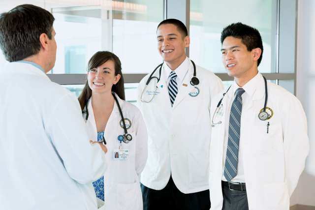 Medical students smiling and looking at a teacher.