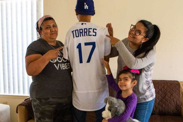 Family holding a 'Torres 17' jersey in a living room