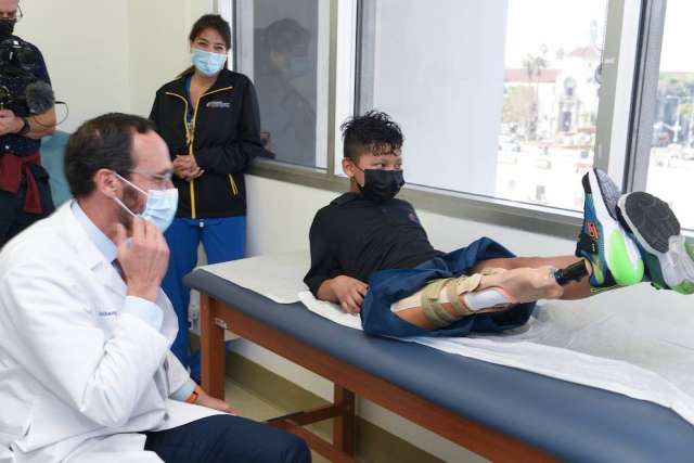 A patient demonstrates mobility on a treatment table while a doctor observes.