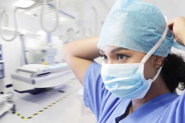 Healthcare professional adjusting a surgical cap in an operating room.