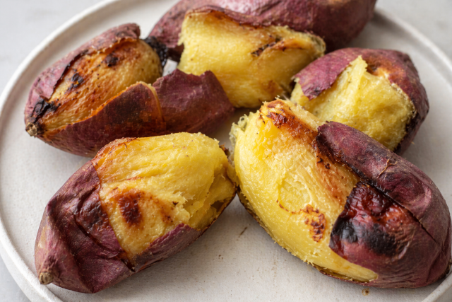 Roasted purple-skinned sweet potato halves on white plate