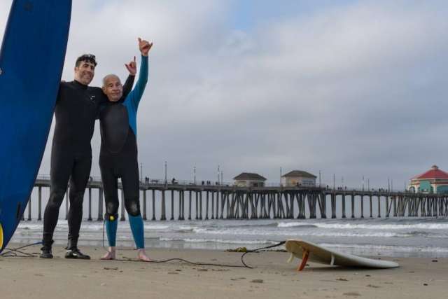 Dr. Sassoon and Robert Lombard  throwing up a "hang loose" sign with their hands on the beach