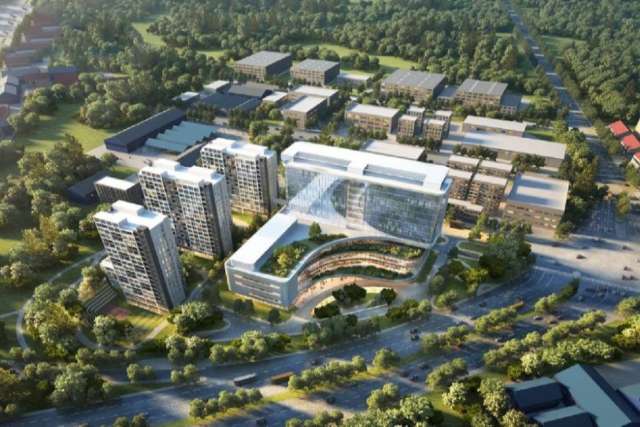 Aerial view of a modern campus with multiple glass buildings, green spaces, and surrounding roads.
