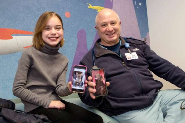 Smiling woman and Dr. Gary Satou seated, holding smartphones displaying photos