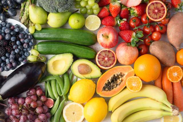 Fruits and vegetables on a table displayed in the colors of the rainbow