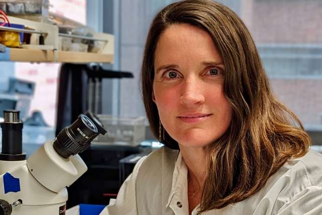 Anne Churchland sits in front of a microscope in her lab.